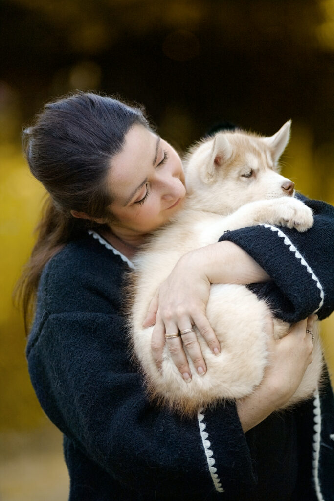 Portrait naturel en extérieur d'une éleveuse avec son chiot, adapté à une communication professionnelle autour du lien, de la confiance et de l’activité animale.