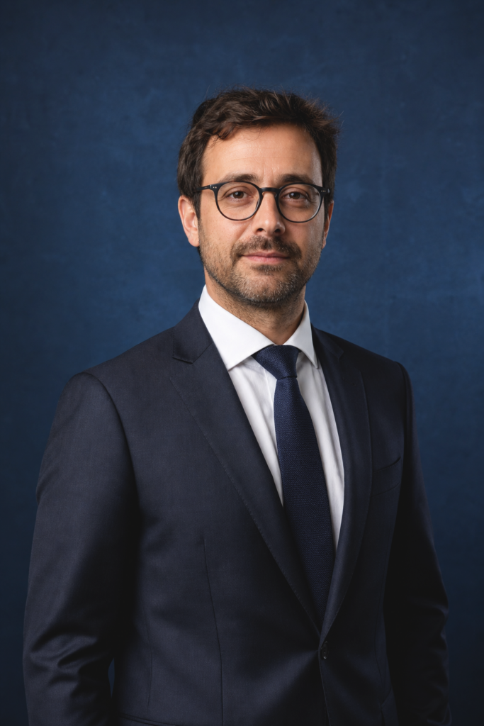 Portrait professionnel d’un homme en costume sur fond bleu, pour une image corporate crédible et soignée.